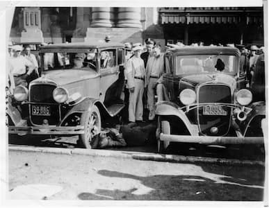 A vintage photo of two Model-T-ish cars on a city street, early 20th century